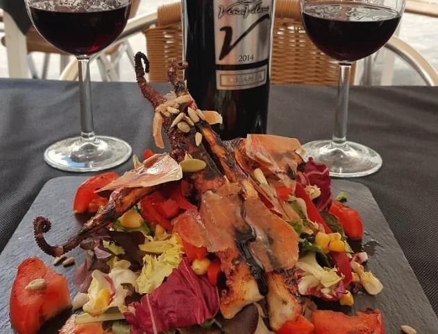 A plate of local specialities with two glasses of red wine